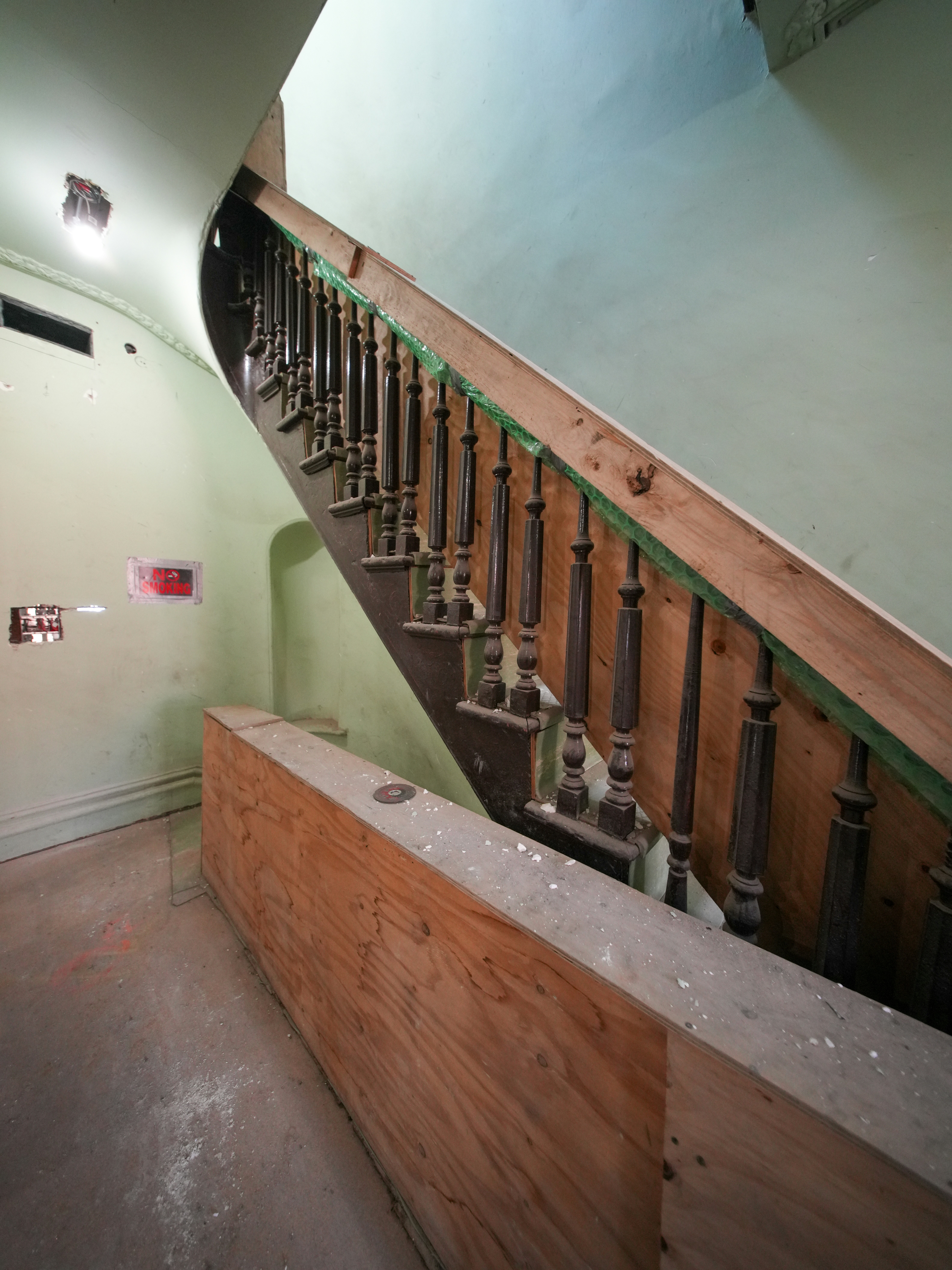 Wooden staircase with ornate balusters and green trim.